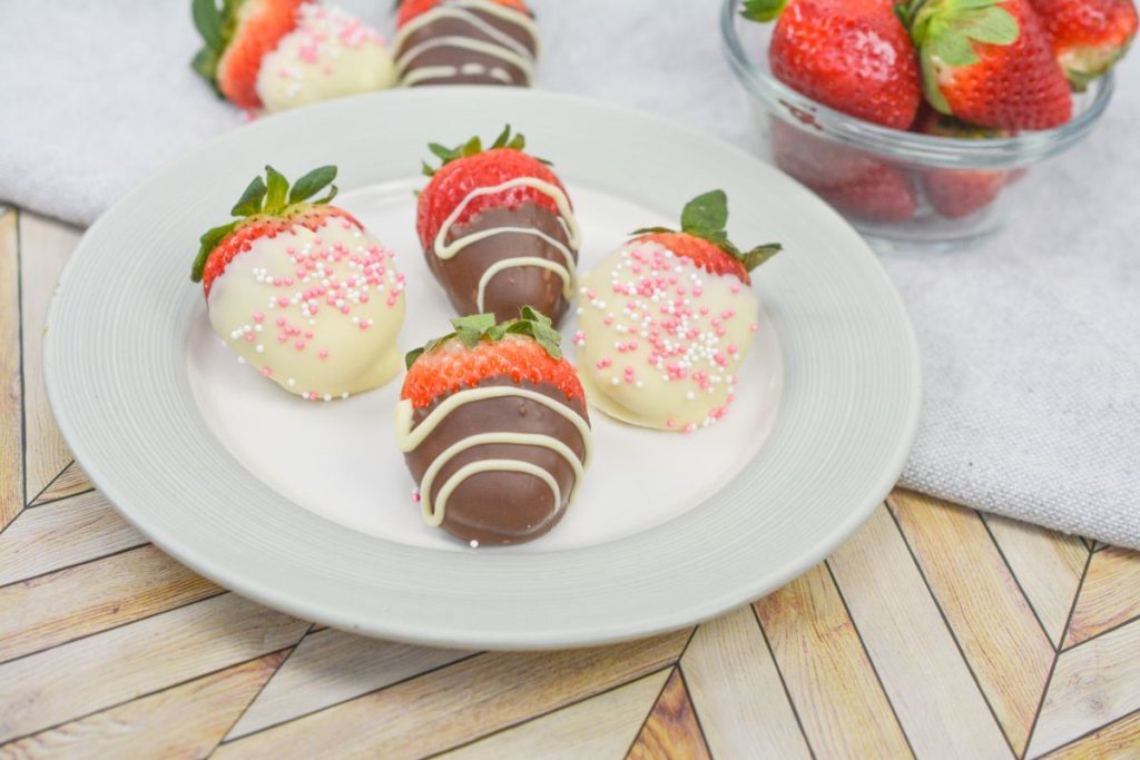 Chocolate covered strawberries on a white plate.