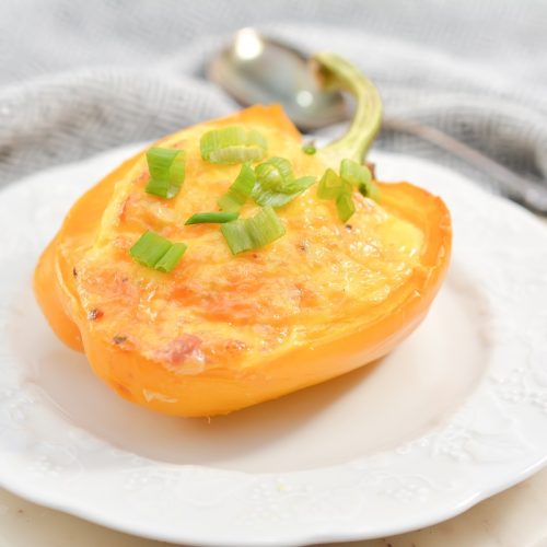 An omelette stuffed pepper on a white plate.