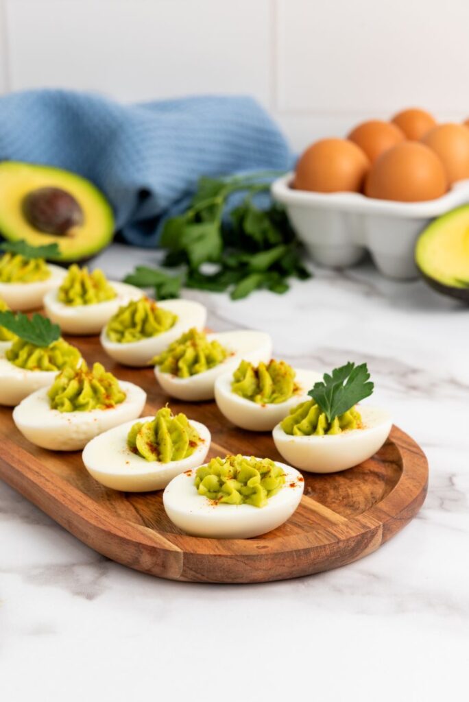Diabetic-Friendly Avocado Deviled Eggs Avocado deviled eggs on a wooden board.