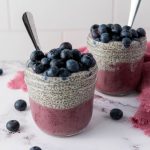 Layered blueberry chia pudding in two mason jars.