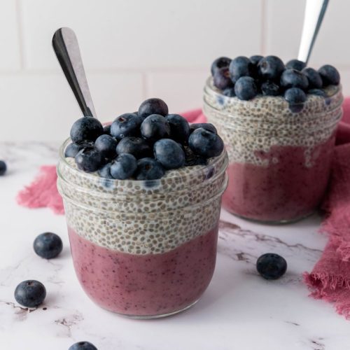 Layered blueberry chia pudding in two mason jars.