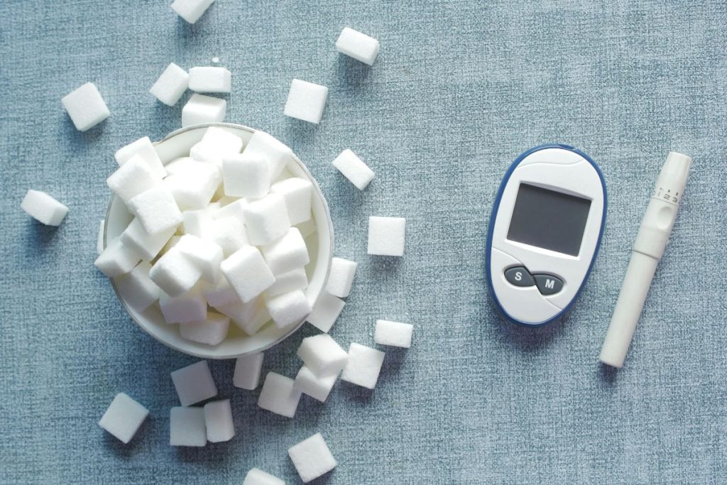 A picture of sugar cubes and a glucometer.