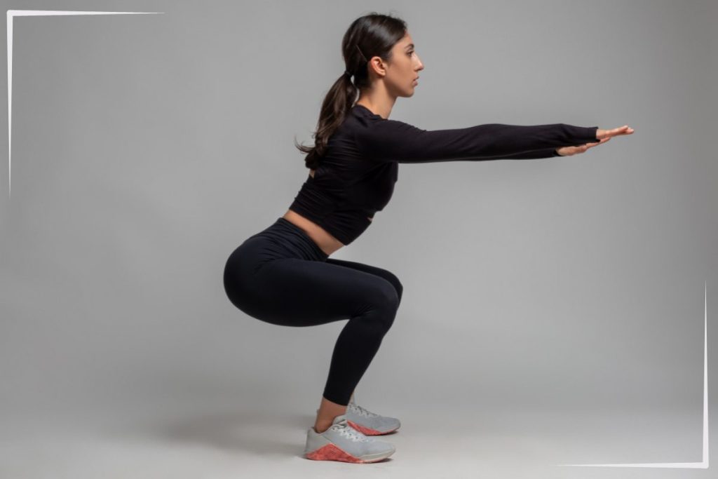 A woman doing squats with a side view.